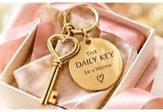 A gold heart key keychain with a round disc in a gift box